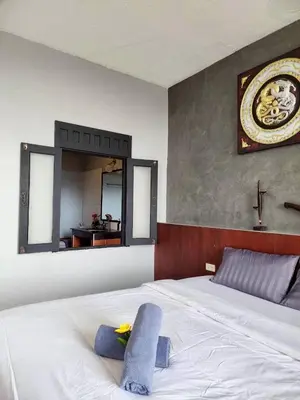 a bedroom with a white bed with a mirror on the wall at The Rest Phuket in Phuket Town