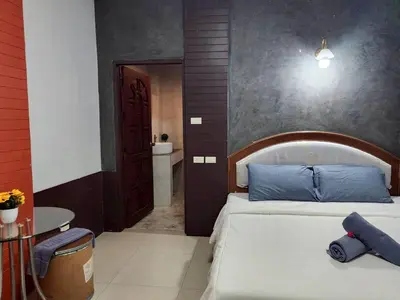 a bedroom with a bed with blue pillows and a bathroom at The Rest Phuket in Phuket Town