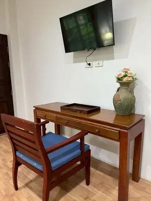 a wooden desk with a television and a vase on it at Floresh Freedom Hostel in Phuket