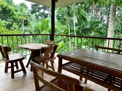 a wooden deck with a wooden table and chairs at Floresh Freedom Hostel in Phuket