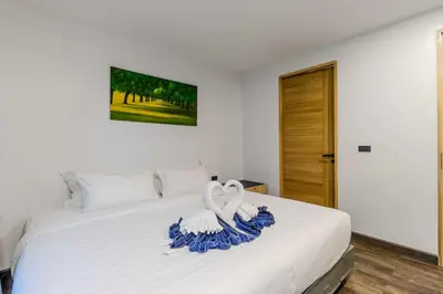 a bedroom with a white bed with blue decorations on it at C248 Condo 3 Min to Nai Harn Beach 1BR with Rooftop Pool in Rawai Beach