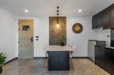 a kitchen with a table and a clock on the wall at C248 Condo 3 Min to Nai Harn Beach 1BR with Rooftop Pool in Rawai Beach