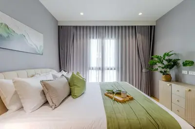 a bedroom with a large white bed with green pillows at C250 Brand new Stay near top beach & Boat Avenue in Thalang