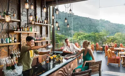 a group of people sitting at a bar at Keemala - Clay Pool Cottage in Kamala Beach