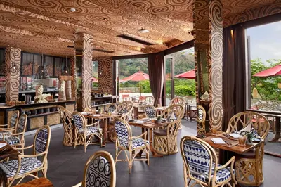 a restaurant with wooden tables and chairs and windows at Keemala - Clay Pool Cottage in Kamala Beach