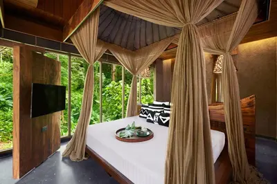 a bedroom with a canopy bed in a room with windows at Keemala - Clay Pool Cottage in Kamala Beach
