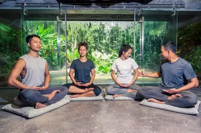 a group of people sitting in a pose in meditation at Keemala - Tree Pool House in Kamala Beach