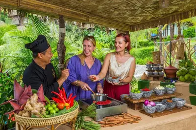 a group of people standing around a table with food at Keemala - Tree Pool House in Kamala Beach
