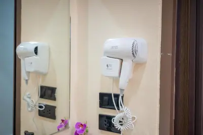 a hair dryer hanging on a wall with a mirror at Amaleena Pool Access Suites in Ban Bang Chak