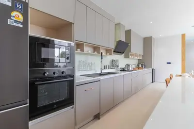 a large kitchen with white cabinets and black appliances at V271 Smart Villa Full Amenities Best Stay Escape in Thalang