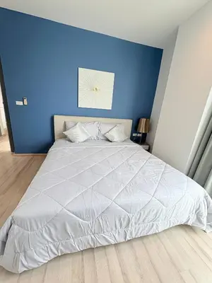 a bedroom with a white bed with a blue wall at The closest accommodation next too central Mall in Ban Rangeng