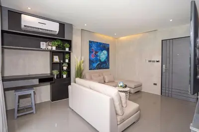 a living room with a white couch and a tv at Deluxe 1BR Pool view 58SQM in Kamala Condo Citygate P302 in Kamala Beach