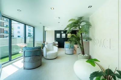 a lobby with chairs and palm trees in a building at 1BR near Laguna, Space Cherngtalay, Bangtao beach by Pat in Ban Thalat Choeng Thale