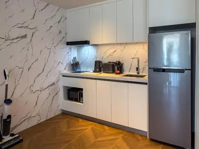 a kitchen with white cabinets and a stainless steel refrigerator at Sunshine Layan Beach Resort 2 bedroom #84192 in Layan Beach