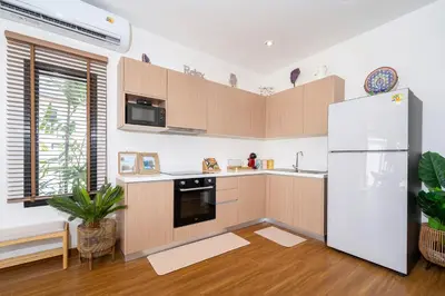 a kitchen with wooden cabinets and a white refrigerator at Holistic Haven Private Pool Villa at Kamala Newest Residence in Kamala Beach