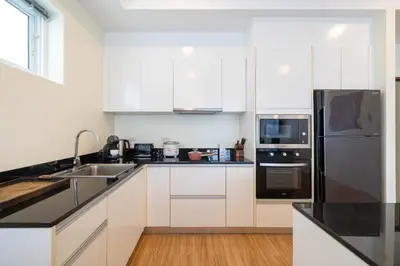 a kitchen with white cabinets and a black refrigerator at Villa Mangosteen 3BR Seaview Pool and Rooftop in Ban Saiyuan (1)