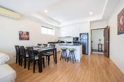 a kitchen and dining room with a black table and chairs at Villa Mangosteen 3BR Seaview Pool and Rooftop in Ban Saiyuan (1)