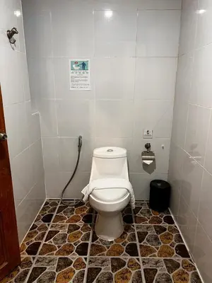 a white toilet in a bathroom with a tiled floor at OYO Dynasty Hotel in Patong Beach