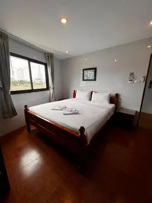 a bedroom with a large bed with white sheets and a window at OYO Dynasty Hotel in Patong Beach