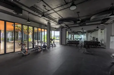 a gym with several exercise bikes in a room with windows at Suite Ostia with Gym Pool Access-Bellevue Lagoon in Laguna Phuket