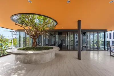 a building with a tree in the middle of a lobby at Suite Ostia with Gym Pool Access-Bellevue Lagoon in Laguna Phuket