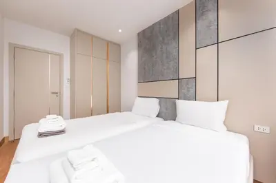 two beds in a room with two white beds at Suite Avila 2BR Gym Pool Close to Beach in Laguna Phuket