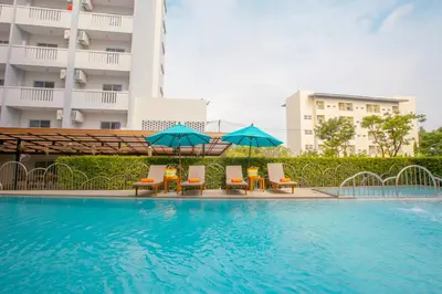 a swimming pool with chairs and umbrellas in front of a building at Recenta Phuket Suanluang by Deevana in Phuket Town