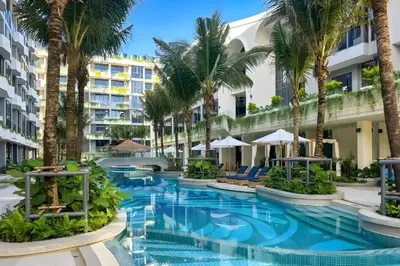 a swimming pool with palm trees and buildings at Layan Green Park Studio by Search Estate in Phuket