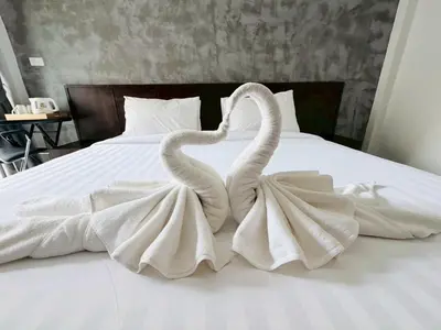 two white swans are sitting on a bed at The Sense in Patong Beach