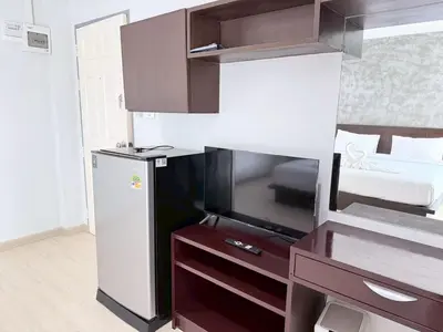 a room with a bed and a desk with a television at The Sense in Patong Beach