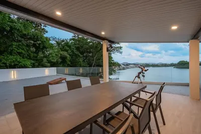 a table and chairs on a patio with a view of a river at Lakeside 5-BR New Pool Villa in Gated Community in Chalong
