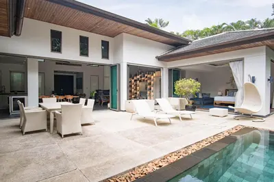 a patio with white chairs and a swimming pool at Luxury Pool Villa a Short Walk from Bangtao Beach in Bang Tao Beach