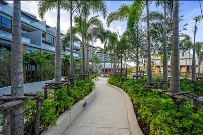 a walkway with palm trees in front of a building at Private Villa at Mida Grande Resort in Surin Beach
