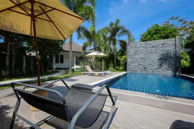 a swimming pool with two chairs and an umbrella at Nua Tone Pool Villa I Mountain View I Bangtao Beach in Ban Thalat Choeng Thale