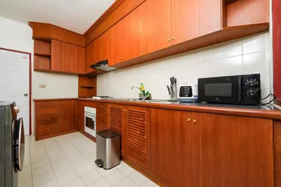 a kitchen with wooden cabinets and a microwave at Blue Canyon Golf and Country Club Villa 97 in Ban Muang Mai (1)