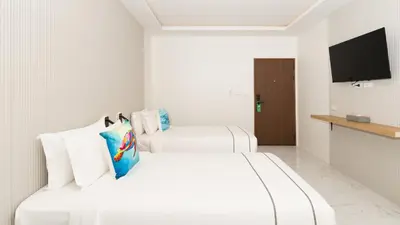 two white beds in a room with a television at Laoteng Boutique Hotel in Phuket Town