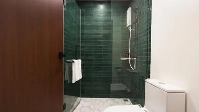 a green tiled bathroom with a toilet and a shower at Laoteng Boutique Hotel in Phuket Town