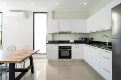 a kitchen with white cabinets and a wooden table at 3-Story Pool Villa Near Kata Beach - UTK 4 in Kata Beach
