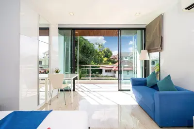 a bedroom with a blue couch and a balcony at 3-Story Pool Villa Near Kata Beach - UTK 4 in Kata Beach