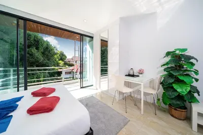 a bedroom with a bed and a table and a plant at 3-Story Pool Villa Near Kata Beach - UTK 4 in Kata Beach