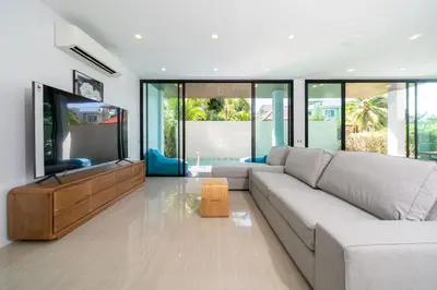 a living room with a couch and a flat screen tv at 3-Story Pool Villa Near Kata Beach - UTK 4 in Kata Beach