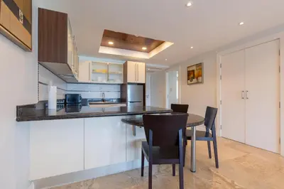 a kitchen with white cabinets and a table and chairs at Sea view apartment at Bel Air Panwa in Ban Ao Makham