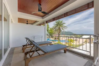 a balcony with a lounge chair and a view of the ocean at Sea view apartment at Bel Air Panwa in Ban Ao Makham