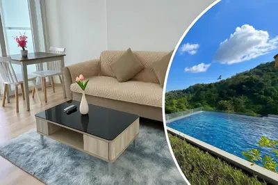 a living room with a couch and a view of a lake at Elegant Stay with 360 degree Panoramic Rooftop Pool in Ban Sam Kong