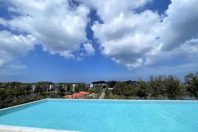 a blue swimming pool with a blue sky and clouds at Private apartment at Skypark in Laguna by Lofty in Laguna Phuket