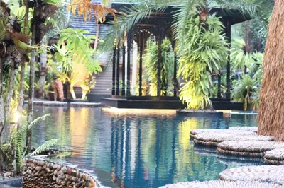 a pool of water with palm trees and a building at Villa Habeebee in Ao Nang Beach