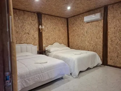 a bedroom with two beds and a air conditioner at Fadel Bungalow ฟาดิลบังกะโล in Ban Lo Pa Ret