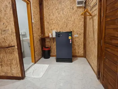 a small refrigerator in a room with a toilet at Fadel Bungalow ฟาดิลบังกะโล in Ban Lo Pa Ret