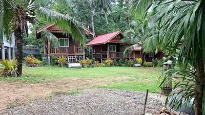 a house in the middle of a yard with trees at Fadel Bungalow ฟาดิลบังกะโล in Ban Lo Pa Ret