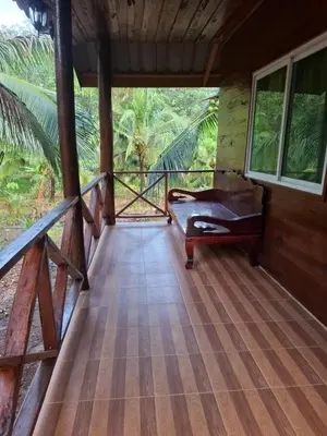 a porch of a house with a bench on a wooden floor at Fadel Bungalow ฟาดิลบังกะโล in Ban Lo Pa Ret